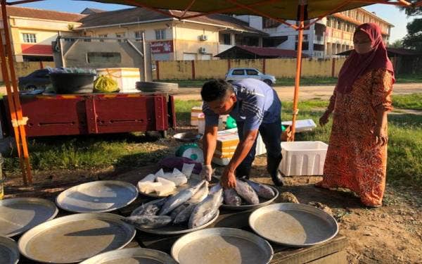 Mohamad Nasir ketika melayani pelanggannya di pasar cabang tiga, di Pengakalan Chepa, Kota Bharu.