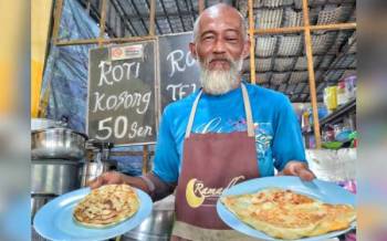 Mustafa menunjukkan roti canai kosong berhatga 50 sen (kiri) dan roti canai telur RM1 yang dijual di warungnya di Bukit Pulau, Bukit Katil pada Selasa.