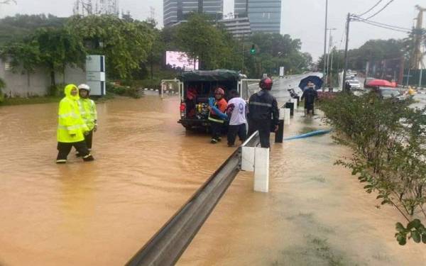Petugas DBKL sedang melakukan kerja mengalihkan air bertakung dan kawalan lalu lintas di Jalan Dutamas. - Foto FB DBKL