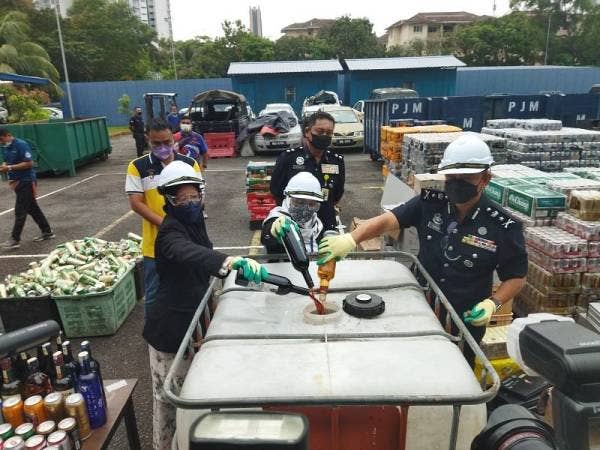 Habibi (kanan) ketika melupuskan minuman keras di Balai Polis Alam Damai pada Rabu.