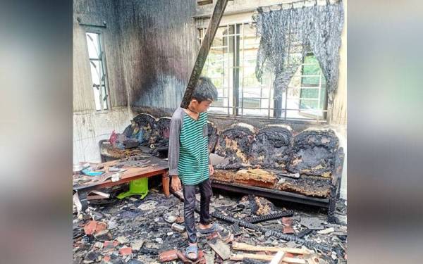 Anak Jasnizah, Zulhelmi Mohd Farid melihat keadaan ruang tamu rumah yang terbakar.