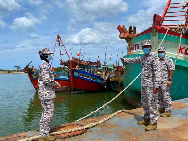 Khairun Dalilah (kiri) menunjukkan bot-bot pukat tunda milik nelayan Vietnam yang berjaya ditahan oleh Maritim Malaysia Kelantan.