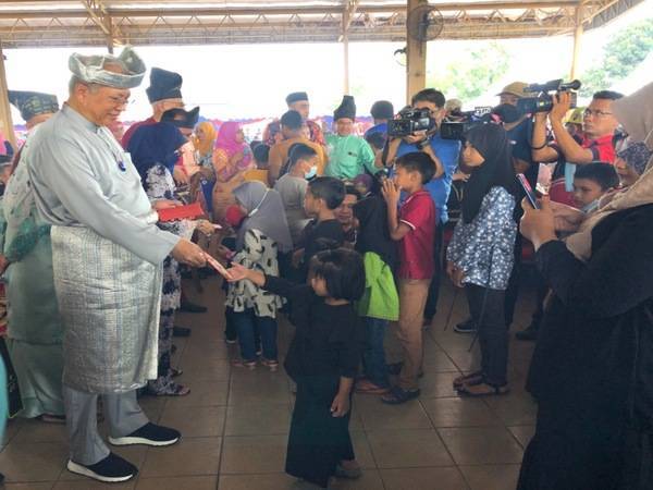 Menteri Komunikasi dan Multimedia, Tan Sri Annuar Musa (kiri) menyampaikan duit raya kepada kanak-kanak yang hadir Majlis Ramah Mesra Aidilfitri Menteri Komunikasi dan Multimedia bersama Komuniti Keluarga Malaysia dan Rakyat Kelantan di Kompleks Yayasan Kemiskinan Kelantan Padang Kala, Kota Bharu, pada Sabtu