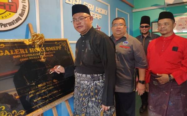 Noh (kiri) menandatangani plak sempena Perasmian Mesyuarat Agung PIBG dan Perasmian Galeri Hoki SMK Pengkalan Permatang pada Ahad.