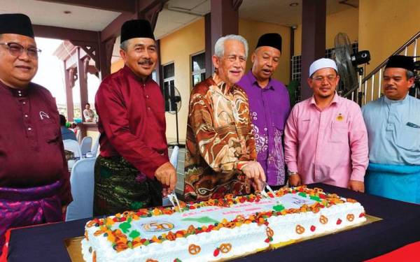 Nik Roslan (dua dari kiri) bersama Kamarudin (empat dari kanan) memotong kek pada majlis Rumah Terbuka Aidilfitri KADA di Kota Bharu pada Isnin.