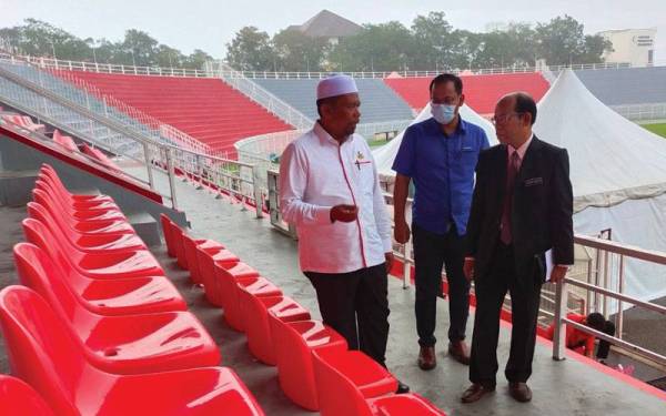 Wan Roslan (kiri) turun padang meninjau kerja-kerja naik taraf Stadium Sultan Muhammad IV di Kota Bharu pada Isnin.