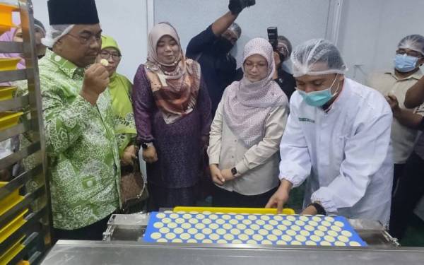Muhammad Sanusi (kiri) merasai coklat yang dikeluarkan oleh kilang tempatan milik CNW Jitra Manufacturing di Taman Industri Keda Napoh, dekat sini pada petang Isnin.