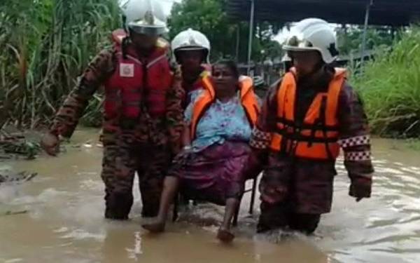 Anggota bomba membantu memindahkan mangsa yang terjejas banjir di Gurun, Kedah.