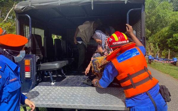 Anggota APM Kuala Muda membantu seorang mangsa banjir untuk dibawa ke tempat kawasan selamat di Mukim Gurun, Sungai Petani pada Khamis.