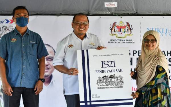 Ahmad Amzad (tengah) menyerahkan benih padi IS21 kepada wakil petani Hazmi Othman (kanan) pada Majlis Penyerahan Benih Padi IS21 sempena sempena Jelajah Aspirasi Keluarga Malaysia (AKM) di Kampung Kubang Tangga, pada Jumaat. - Foto Bernama