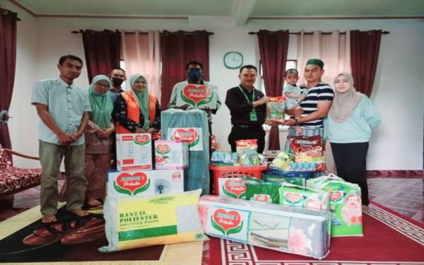 Pengurus Besar Econsave Wilayah Utara Bahagian Satu, Zamzuri Mansor (tiga kanan) menyampaikan sumbangan Econsave Prihatin kepada keluarga Muhammad Izzat Rafael.
