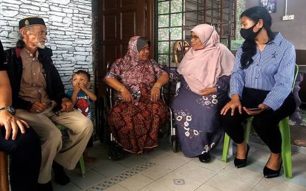 Siti Zailah (dua dari kanan) menyantuni mangsa banjir, Azmi Udin (tiga dari kanan) ketika menyampaikan bantuan pasca banjir pada majlis sumbangan perabot terpakai dari Singapura untuk mangsa banjir di Ampangan, hari ini. Foto Bernama
