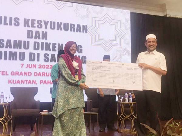Azinah (kiri) menerima replika cek bernilai RM30,000 daripada Syed Ibrahim dalam Majlis Kesyukuran dan Jasa Mu Dikenang, Budi Mu Disanjung anjuran persatuan terbabit pada Selasa.