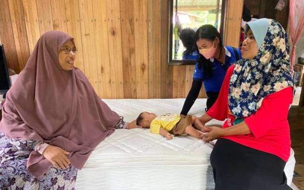 Siti Zailah (kiri) beramah mesra dengan salah seorang penerima sumbangan tilam dan katil di Kampung Bendang Perol, Rantau Panjang pada Rabu.