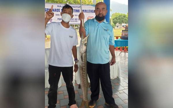 Md Zali (kanan) bersama pemancing memegang ikan alu-alu seberat 6.3 kilogram yang dipancing di Lumut Waterfront.