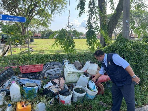 Zakaria (kanan) memeriksa bekas-bekas takungan air di hadapan sebuah numah di Taman Meru Indah di sini pada Jumaat.