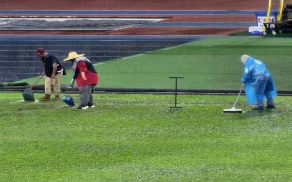 Beberapa petugas sedang menolak air yang bertakung menggunakan penyodok sampah di Stadium Nasional, Bukit Jalil pada Sabtu.