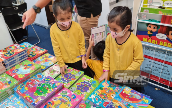 Adik beradik kembar, Nur Iman Hasna dan Nur Iman Husna,5, tertarik memilik buku mewarna di reruai Karangkraf.