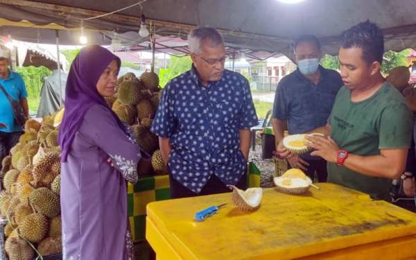 Mohd Al Azzahari (dua dari kanan) melayan pelanggan yang mahu membeli durian di gerainya di di Jalan Langgar, Alor Setar.