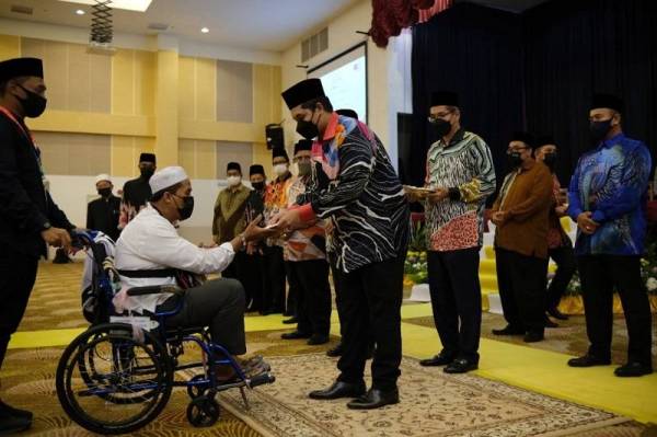 Tengku Muhammad Ismail menyampaikan sumbangan kepada salah seorang jemaah haji yang akan berlepas ke KLIA dari LTSM di Kuala Nerus pada malam Isnin.