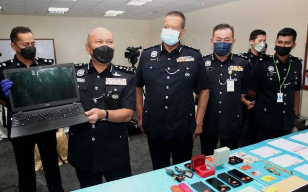 Mohd Kamarudin menunjukkan barangan yang dirampas daripada pasangan suami isteri yang disyaki terlibat dengan penipuan emel.