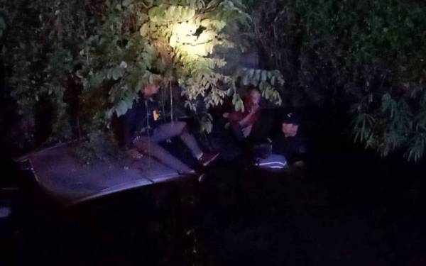 PATI berkenaan terpaksa naik ke atas bumbung kereta untuk mengelakkan dari ditengelami air. Foto Bomba