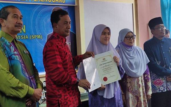 Abdul Muie (dua dari kiri) menyampaikan slip keputusan SPM 2021 kepada Nurul Nadhirah Husna Shahmuzir, pelajar SMA (Atas) Sultan Zainal Abidin yang memperoleh 10 A pada Khamis.