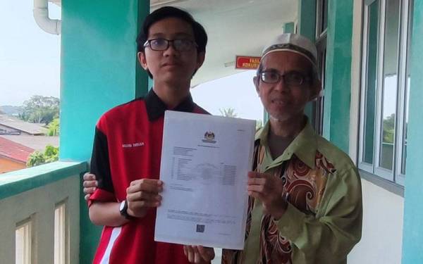 Muhammad Imran (kiri) bersama bapanya menunjukkan keputusan cemerlang iaitu 12A yang diperolehi dalam SPM 2021.