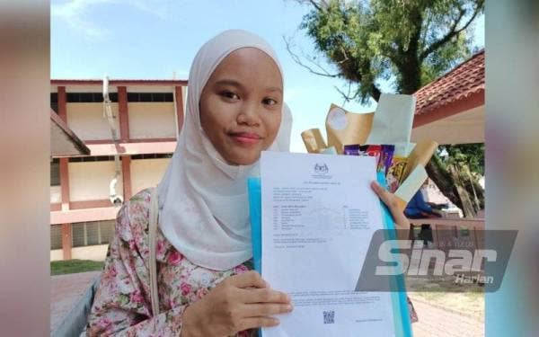 Cahaya Iman menunjukkan keputusan peperiksaan SPM ketika ditemui di SMK Gunung Rapat pada Khamis.