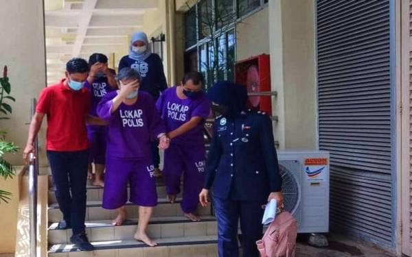 Tertuduh (dua dari kiri) menutup mukanya dengan tangan selepas dibawa keluar dari Mahkamah Sesyen Raub pada Jumaat.