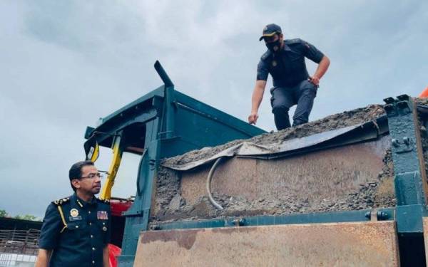 Pengarah Penguat Kuasa KPDNHEP Azman Adam(kiri) menunjukkan lori yang telah diubah suai untuk mengisi minyak diesel menerusi serbuan di sebuah stor haram di Klang pada Rabu lalu.