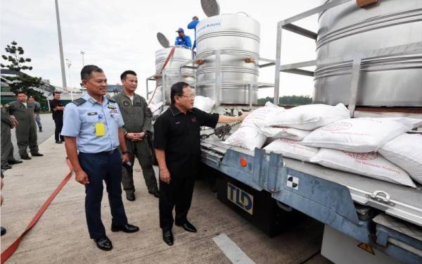 Ahmad (kanan) melihat larutan garam yang akan disembur di ruang udara empangan menggunakan pesawat C-130 Hercules milik TUDM pada Sabtu. - Foto MAFI