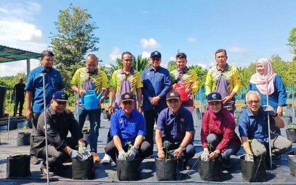Ronald (duduk, tiga dari kanan) melakukan semaian anak pokok ketika lawatannya ke Pusat Pemasaran Agromakanan Fama di Manong, Kuala Kangsar pada Sabtu.