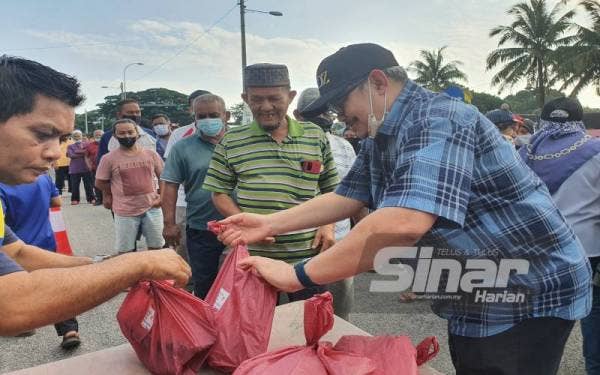 Dzulkifli (kanan) menyampaikan bantuan berupa ikan cencaru kepada penduduk di Tasek Gelugor.