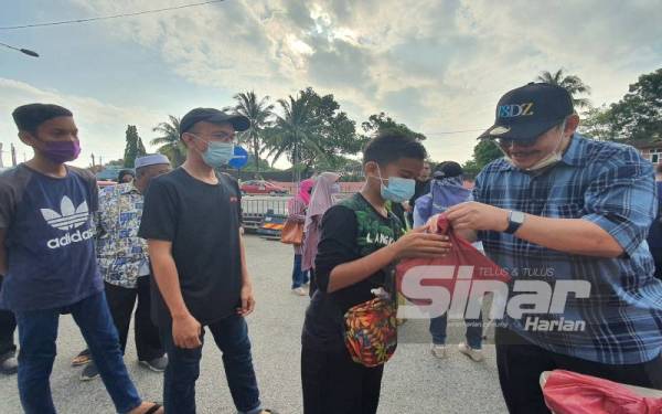 Dzulkifli (kanan) menyampaikan bantuan berupa ikan cencaru kepada penduduk di Tasek Gelugor.