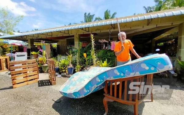 Rosli menjemur tilam yang basah akibat banjir kilat yang berlaku di Jalan Perepat pada Jumaat.