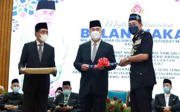 Tengku Mohamad Rizam menyampaikan Kit Promosi Wakaf kepada Pemangku Ketua Polis Kelantan, Datuk Muhamad Zaki Harun pada Majlis Pelancaran Bulan Wakaf Majlis Agama Islam dan Adat Istiadat Melayu Kelantan pada Isnin.