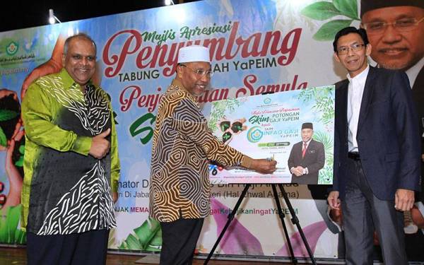 Idris menyempurnakan gimik pelancaran SIG disaksikan oleh Mohd Redza Shah (kiri) dan Awang (kanan) di Hotel Tenera, Bangi.