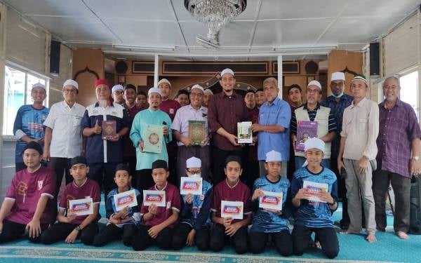 Hashim (lima dari kanan) menyerahkan wakaf al-Quran kepada Najakhul Imam pada Program Ziarah ke Maahad Tahfiz Mandarin di Pulau Ketam, Pelabuhan Klang pada Rabu.