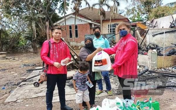 Mohammad (kanan) menyerahkan sumbangan kepada Siti Katijah di tapak rumah mereka yang terbakar di Taman Uda di sini pada Khamis.