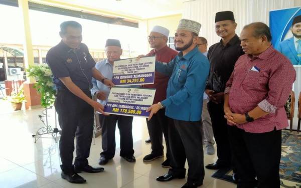 Nik Muhammad Zawawi (tiga dari kanan) menyampaikan Peruntukan Skim Pemilikan Jentera dan Peralatan Kecil Peladang ketika mengadakan lawatan kerja ke Pejabat Pertubuhan Peladang Kawasan Gunung Semanggol/Selinsing, di sini pada Khamis.