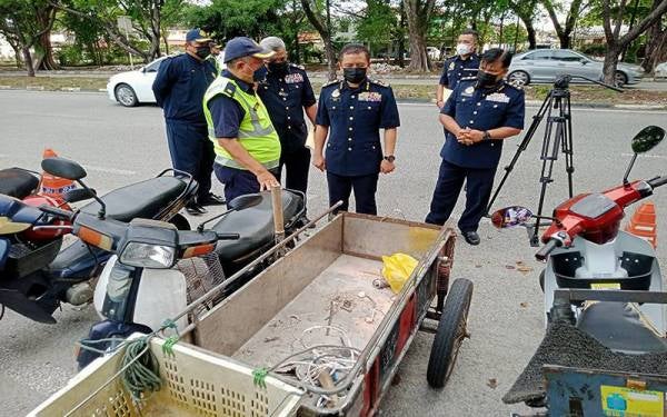 Aedy Fadly (dua, kanan) melihat motosikal yang disita dalam Operasi Khas Pemandu Warga Asing (Ops PeWA) di Persiaran Budiman, Seksyen 25, Shah Alam pada Khamis.