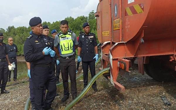Kamarul Zaman (depan) menunjukkan tangki treler yang digunakan sindiket penyelewengan diesel bersubsidi di Sungai Sauk, Tanjung Belungkor di Kota Tinggi pada Ahad.