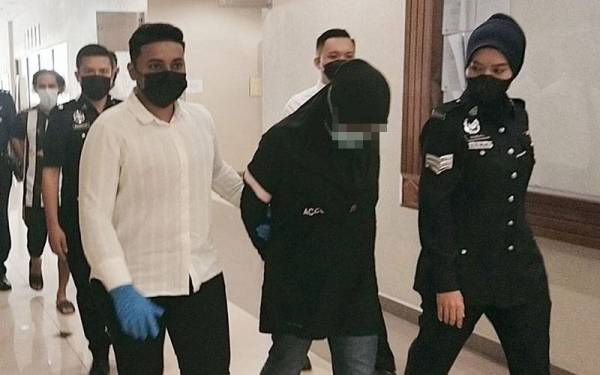 Tertuduh diiringi anggota polis ketika dibawa ke mahkamah untuk sebutan kes melibatkan 25 tuduhan menipu membabitkan tawaran pakej pembelian emas 916 ke atas empat mangsa tahun lalu dan awal tahun ini.