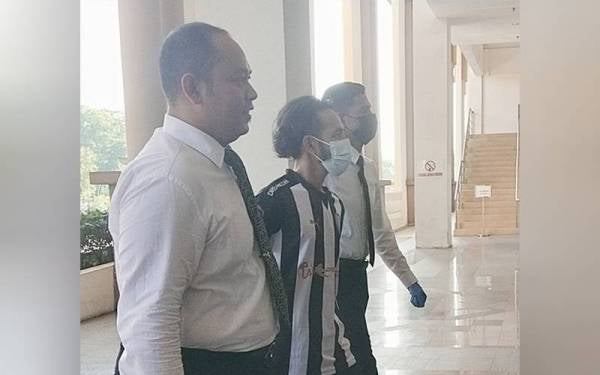 Tertuduh diiringi anggota polis ketika dibawa untuk sebutan kesnya di Mahkamah Majistret pada Isnin.