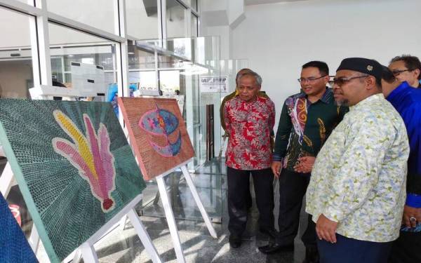 Fadzli (dua dari kiri) bersama Muhammad Nasir (kiri) dan Mohd Khairuddin (kanan) melihat lukisan yang dihasilkan melalui kalimah ALLAH.