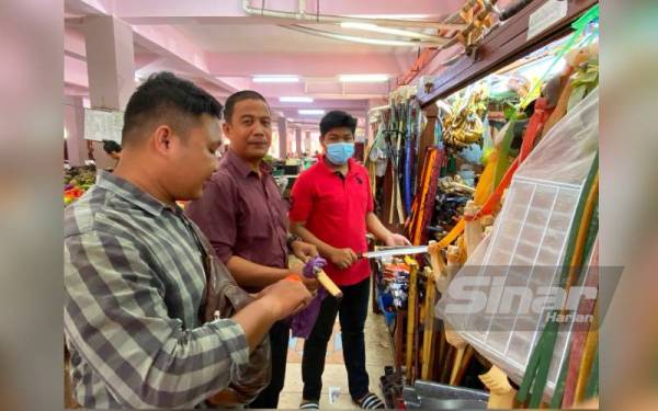 Irfan (kanan) melayan pelanggan yang datang ke gerainya bagi mendapatkan kelengkapan korban.