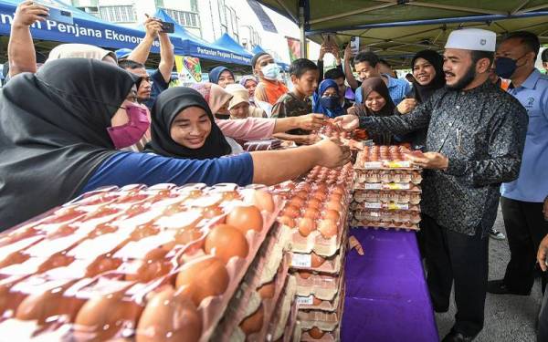 Dr Nik Muhammad Zawawi (kanan) turut membantu menjual telur ayam kepada orang ramai pada Program Khas Jualan Terus Dari Ladang Keluarga Malaysia (JTDLKM) di Perkarangan Pusat Khidmat Ahli Parlimen Pasir Puteh pada Sabtu. - Foto Bernama