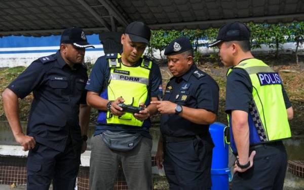 Kamarul Zaman Mamat (dua, kanan) menyaksikan Fathuddin (dua, kiri), mengendalikan dron yang digunakan untuk memantau lalu lintas dalam Op Lancar di Jalan Tebrau, di sini pada Sabtu. - Foto Bernama 
