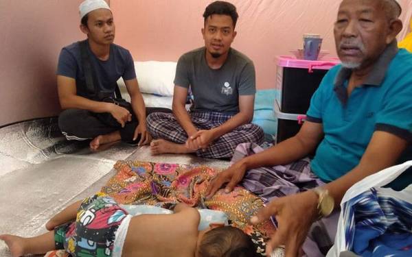 Abd Rahman Said (kanan) bersama anak tirinya, Khairul Asyraf Nor Azman (tengah) ketika ditemui di PPS SMK Jerai, Baling, dekat sini.